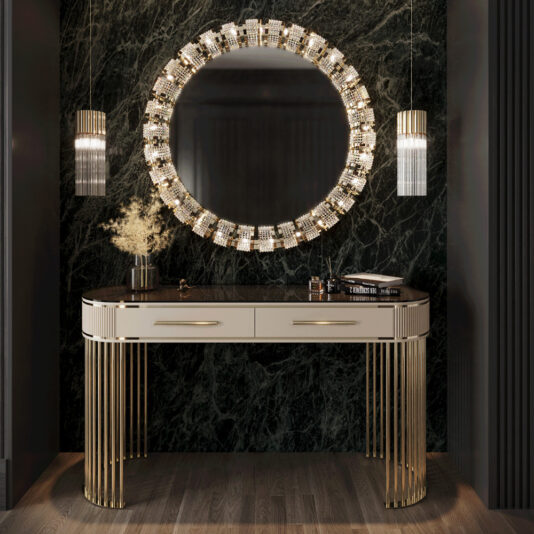 Art Deco Style Ribbed Console Table The Art Deco Style Ribbed Console Table in sleek black and gold, with two drawers, creates an elegant vanity setup beneath a round illuminated mirror. It's flanked by cylindrical pendant lights and adorned with a decorative vase against a dark marble wall.