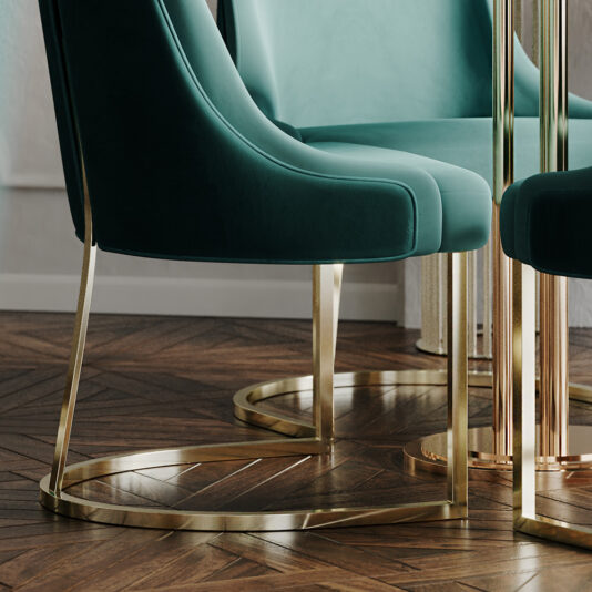 A close-up of two High End Contemporary Dining Chairs showcases their modern green upholstery with gracefully curved backs and sleek gold legs. A portion of a polished gold table leg is also visible. The dining set rests on a stylish wooden herringbone floor, enhancing the elegant and contemporary ambiance.