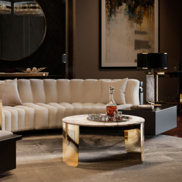 The image showcases a luxurious living room, featuring a plush, white, curved sofa; the Modern Marble Round Coffee Table holding a decanter of liquor and glasses; a round wall mirror; a modern painting on the wall; and stylish table lamps.