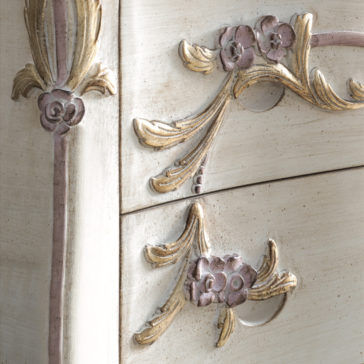 Close-up of the Carved Italian Chest Of Drawers. The detail showcases ornate floral and leaf designs in soft pastel shades of pink, gold, and cream. The surface features an antique, distressed finish, giving it a vintage, elegant appearance.