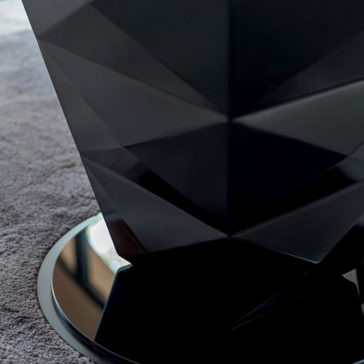 Modern Italian Glass Dining Set Close-up of a faceted black sculpture with a geometric design placed on a mirrored circular base. The surface around the base is covered with a light gray carpet, adjacent to the chic Modern Italian Glass Dining Set. The reflection on the mirror shows part of the room's window.