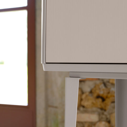 A close-up image of the Modern Lacquered Bar Cabinet highlights its clean lines and minimalist design. The background features a partial view of a window with natural light streaming in and a textured stone wall.