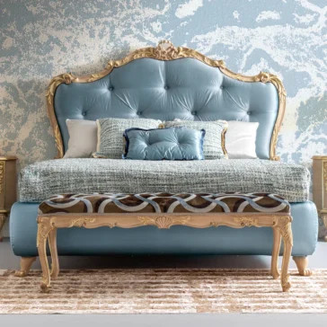 Button Upholstered Rococo Style Bed The Button Upholstered Rococo Style Bed features a tufted light blue headboard with ornate golden trim and comes with decorative pillows and a textured blanket. A matching upholstered bench with gold accents is at the foot, set against a blue textured wall backdrop.