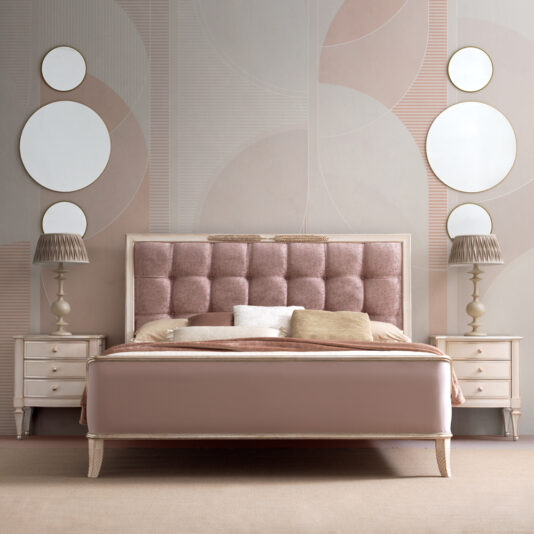 A stylish bedroom with a Feather Design Button Upholstered Sleigh Bed featuring a tufted headboard in blush tones. Two round mirrors are symmetrically hung on a textured wall behind the bed. Two beige nightstands with lamps flank the bed, complementing the room's soft, modern decor.