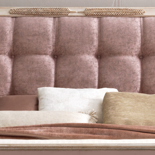 A close-up view of the Feather Design Button Upholstered Sleigh Bed showcases its tall, plush, tufted headboard in a muted pink color. The bed is adorned with several pillows in shades of white, beige, and pink, accompanied by a cozy throw blanket in soft complementary hues. The setting exudes an elegant and inviting atmosphere.