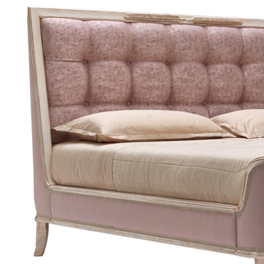 A close-up view of the luxurious Feather Design Button Upholstered Sleigh Bed reveals its tall, tufted headboard upholstered in a soft pink fabric. The bed is dressed with beige sheets and matching pillows, while the frame showcases elegant feather design detailing in a light cream color.