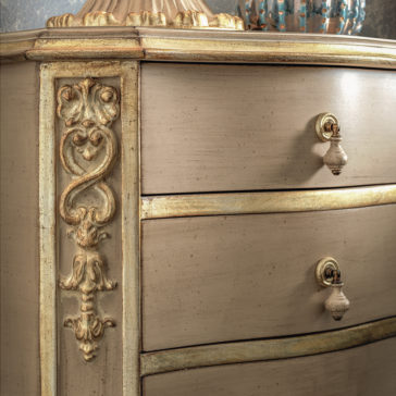 Ornate Classic Style Chest Of Drawers A close-up of the Ornate Classic Style Chest Of Drawers reveals its elegantly antique design with intricate carvings and golden accents. This classic dresser boasts two rounded drawers with vintage handles, highlighting detailed craftsmanship and a harmonious blend of beige and gold tones.