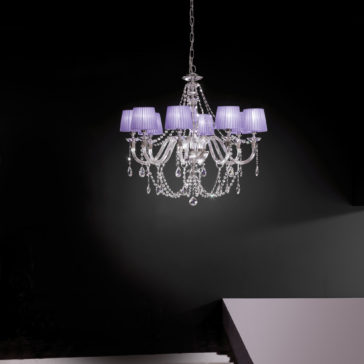Clear Glass Chandelier With Pleated Shades The Clear Glass Chandelier With Pleated Shades, adorned with hanging glass ornaments, is suspended from the ceiling against a dark background. This chandelier boasts multiple curved arms and intricate detailing, creating an elegant and sophisticated appearance.