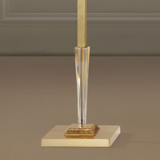 Luxury Classical Floor Lamp A close-up image of the lower part of the Luxury Classical Floor Lamp. The stylish, modern lamp features a square, gold-colored base with a central vertical rod extending upwards. The rod has a clear, faceted section adding an element of elegance and sophistication to the overall design.
