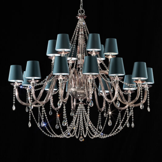 The Large Modern Smoked Glass Chandelier With Shades features multiple curved arms embellished with hanging crystals and draped crystal beads. Each arm supports a blue lamp shade, adding a sophisticated and luxurious touch against the black background, further enhanced by the smoked glass elements.