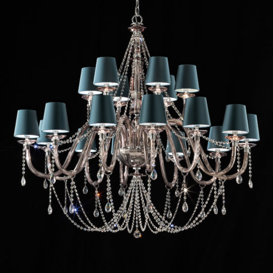 The Large Modern Smoked Glass Chandelier With Shades features multiple curved arms embellished with hanging crystals and draped crystal beads. Each arm supports a blue lamp shade, adding a sophisticated and luxurious touch against the black background, further enhanced by the smoked glass elements.