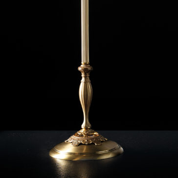 Traditional Amber Blown Glass Floor Lamp A close-up of the lower portion of an ornate, brass table lamp. The lamp features a decorative base with intricate carvings and a fluted column, reminiscent of a traditional design. Set against a black background, the metal has a polished, golden sheen akin to that of the Traditional Amber Blown Glass Floor Lamp.