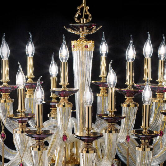 The Candle Style Chandelier With Swarovski® Crystals features multiple gold-finished, candle-like lights each adorned with a flame-shaped bulb. This chandelier is elaborately decorated with intricate details and Swarovski® crystals, all set against a striking black background.