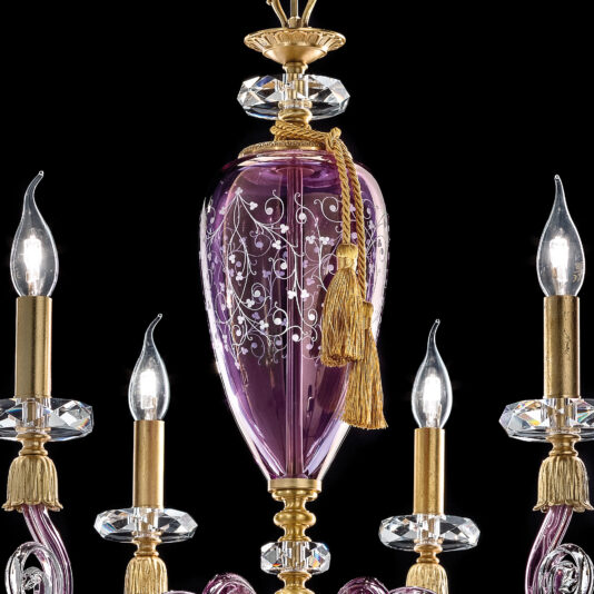 A close-up of the Contemporary Candle Style Glass Chandelier featuring an intricately designed purple glass centerpiece adorned with gold and silver decorations. Four arms extend from the center, each holding a lit, candle-shaped bulb. The chandelier is enhanced with decorative gold tassels and crystal accents.