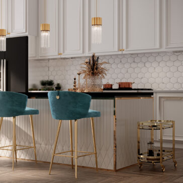 A modern kitchen featuring white cabinets, a hexagonal patterned white backsplash, and a black countertop. Two contemporary velvet bar stools with gold legs sit at a white island with vertical grooves. Hanging above are three pendant lights with gold accents. Nearby sits the Contemporary Curved Drinks Trolley.