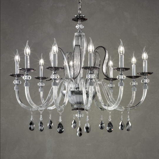 The Modern Chandelier With Swarovski® Crystals features multiple candle-shaped lights, gracefully curved glass arms, and ornate hanging Swarovski® crystals. Set against a gray background, this elegant chandelier emits a warm and inviting glow, enhancing any space with a touch of sophistication and luxury.