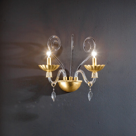 Modern double wall light with crystal drops, featuring two candle-shaped lights and decorative scrollwork, elegantly mounted on a dark textured wall.