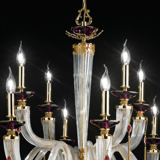 The Swarovski® Crystal Candle Style Chandelier boasts a luxurious design featuring multiple curved glass arms and candle-shaped light bulbs, all intricately detailed with gold accents and adorned with purple glass ornaments. Set against a black background, the brightly shining lights create a glamorous and elegant atmosphere.