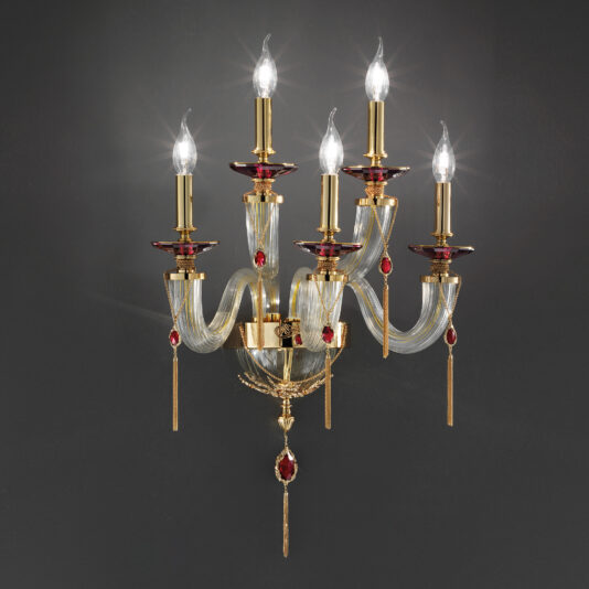 The Swarovski® Crystal Candle Style Wall Light is a luxurious wall-mounted fixture featuring five arms, each adorned with a lit candle-shaped bulb. This chandelier combines gold metal accents and red decorative elements, exuding elegance and opulence against a dark background.