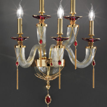 The Swarovski® Crystal Candle Style Wall Light is a sophisticated wall-mounted candelabra featuring five candle-shaped bulbs. This fixture combines gold and clear glass elements, embellished with Swarovski® crystals. The elegantly curved gold arms create an opulent and classic aesthetic in this exquisite candle-style wall light.