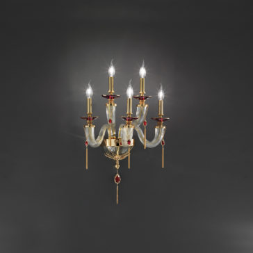 A Golden wall-mounted candelabra-style light fixture with six upward-facing light bulbs, each positioned on a golden arm embellished with red accents. The fixture boasts elegantly curved decorative elements and dangling ornaments, exuding the refined charm of a Swarovski® Crystal Candle Style Wall Light against a dark backdrop.
