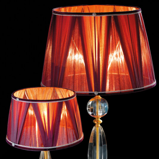 Traditional Glass Table Lamp Two Traditional Glass Table Lamps, featuring pleated red shades, are shown against a black background. The lit bulbs inside emit a warm, glowing light through the fabric. The lamp bases are made of clear glass with a decorative, round design feature.