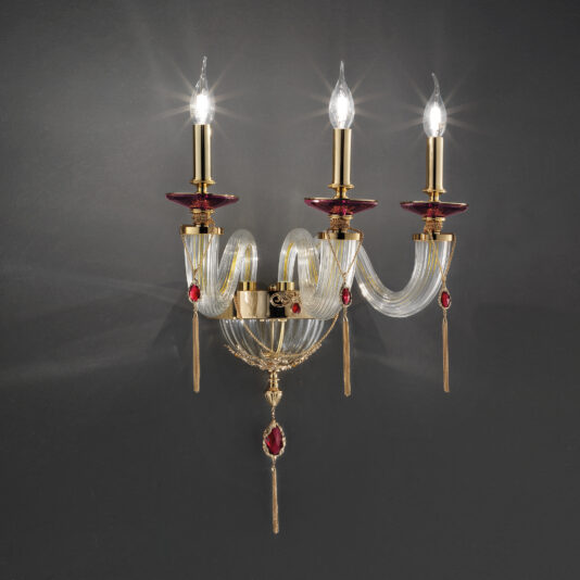 A wall-mounted chandelier features three candle-shaped lights, intricately designed glass arms, and red accents on a dark gray background. This elegant fixture is the Triple Candle Style Wall Light With Swarovski® Crystals.