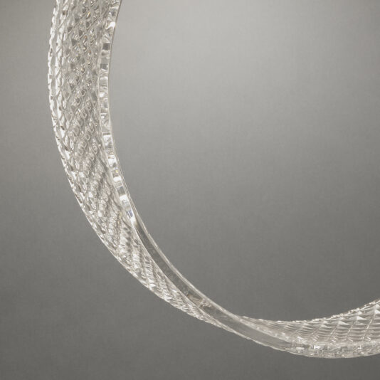 Contemporary Glass Ring Chandelier Close-up of the Contemporary Glass Ring Chandelier, featuring a curved, transparent, and textured glass construction against a gray background. The chandelier displays intricate diamond-shaped patterns and light reflections, offering a sophisticated and delicate appearance.
