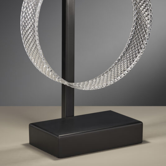 Contemporary Glass Table Lamp Product Name: contemporary glass table lamp
A modern art sculpture featuring a textured metal ring mounted vertically on a black rectangular base. The ring has a diamond pattern surface, with a dark gray background enhancing its reflective quality. The sculpture is reminiscent of the sleek design of the contemporary glass table lamp and is minimalist in nature.