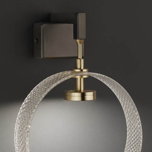 Contemporary Glass Wall Light The Contemporary Glass Wall Light boasts a brass and bronze finish and features a semi-circular, textured glass shade. It softly illuminates against a dark background, highlighting its elegant and modern design.
