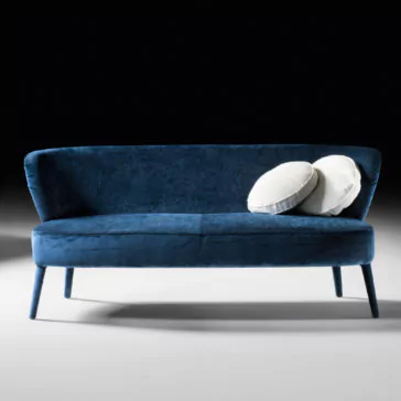 High End Mid Century Style Day Sofa A high-end mid-century style day sofa, adorned in modern blue velvet with sleek, slender legs, is set against a dark background. Two white round pillows are casually placed on the right side of the day sofa. The scene is minimalist and elegant, highlighting the smooth texture of the fabric and sophisticated design.