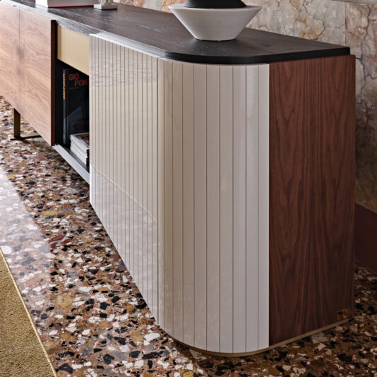 The High End Modern Canaletto Walnut Sideboard, featuring a mix of wooden and white panel finishes, is displayed against a marbled wall. This exquisite piece stands on a terrazzo floor with a black countertop adorned by a decorative bowl, while a few books are visible on its open shelves.