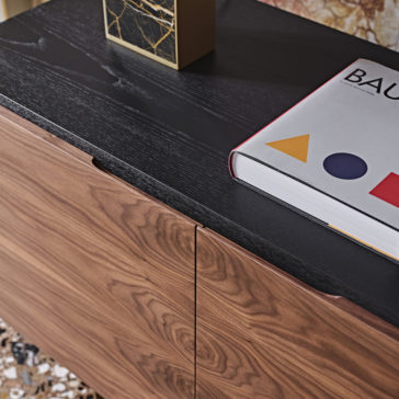 A close-up shot of the High End Modern Canaletto Walnut Sideboard with a dark top surface. A book titled 