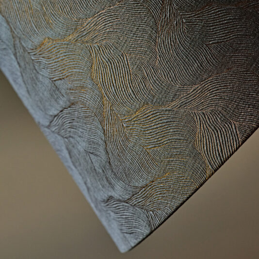 Large Modern Studio Style Floor Lamp Close-up of a textured surface with swirling, wave-like patterns in shades of grey and black. The design consists of fine, parallel lines creating an abstract, intricate appearance. In the background, the Large Modern Studio Style Floor Lamp casts understated illumination, emphasizing the texture and depth.