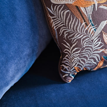 Large Modern Velvet Modular Sofa A close-up of a decorative pillow with an intricate leafy pattern in shades of brown and orange, placed on the Large Modern Velvet Modular Sofa in rich royal blue.