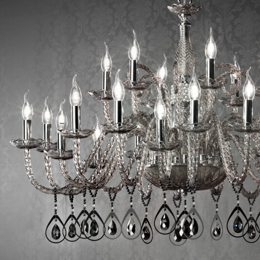 Introducing the Large Smoked Glass Chandelier With Pendant Drops: a luxurious lighting fixture adorned with numerous candle-shaped light bulbs and intricate crystal decorations. This exquisite design showcases ornate crystal arms and tear-shaped pendant drops, perfectly complementing an elegant damask-patterned wallpaper background.
