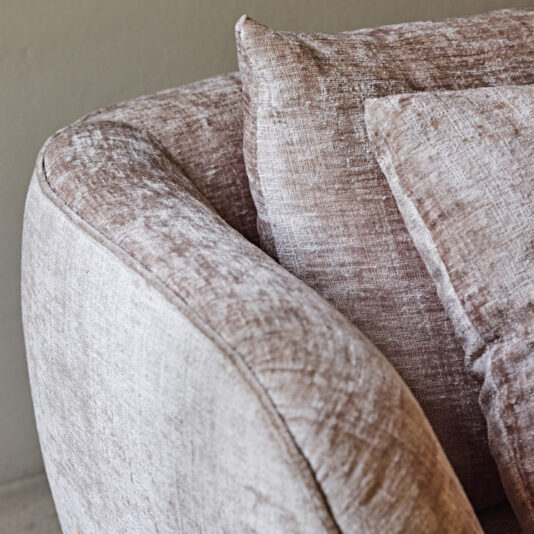 Luxury Contemporary Sofa Close-up shot of the Luxury Contemporary Sofa highlighting its armrest and two cushions. The beige, textured fabric looks soft and slightly worn, imparting a cozy and inviting ambiance to this modern piece of furniture. The background features a neutral gray wall.