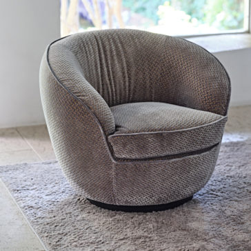 Modern Luxury Swivel Armchair A **Modern Luxury Swivel Armchair** with a textured fabric surface is placed on a light gray rug. The chair is positioned near a large window that lets in natural light, and the background features a neutral-toned floor and a blurred outdoor view.