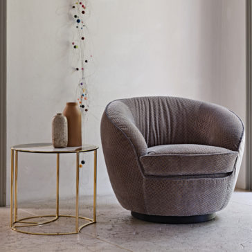 Modern Luxury Swivel Armchair A cozy Modern Luxury Swivel Armchair in gray is positioned next to a round side table with a gold frame and a marble top. The table holds two decorative vases, one brown and one gray. The wall behind features an artistic string and bead decoration, creating a minimalist and modern setting.