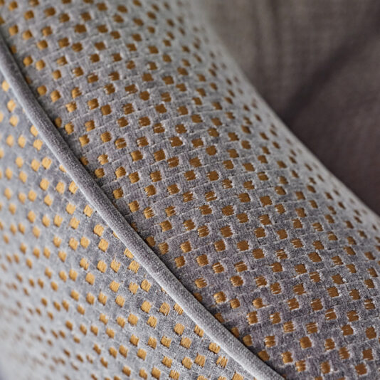 Close-up of the Modern Luxury Swivel Armchair's textured fabric, featuring a pattern of small, golden yellow squares on a gray background. The detailed stitching and exquisite upholstery texture are prominently showcased.