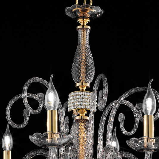 The Smoked Glass Chandelier With Swarovski® Crystals And Pearls features intricate designs with Swarovski® crystals and pearls, accentuated by gold details. Several candle-style light bulbs with flame-shaped tips illuminate the surroundings, creating a stunning visual effect. The chandelier is set against a black background, highlighting its elegance and detail.