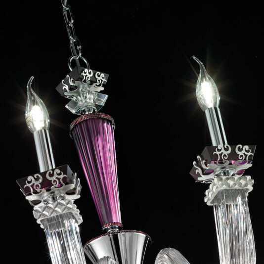 A close-up view of the Elegant Large Amethyst Glass Chandelier showcases its intricate detailing and sophisticated design elements. The chandelier includes three arms holding candle-shaped light bulbs, adorned with decorative metalwork and reflective surfaces, all set against a black background.
