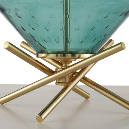 Close-up of the Hand Blown Glass Table Lamp featuring a teal, translucent glass bowl with a bubble-like texture on its surface, supported by a gold-toned metal stand. The stand is designed with intersecting rods that give it a modern, geometric appearance, reminiscent of an elegant table lamp. The lamp is placed on a white surface.