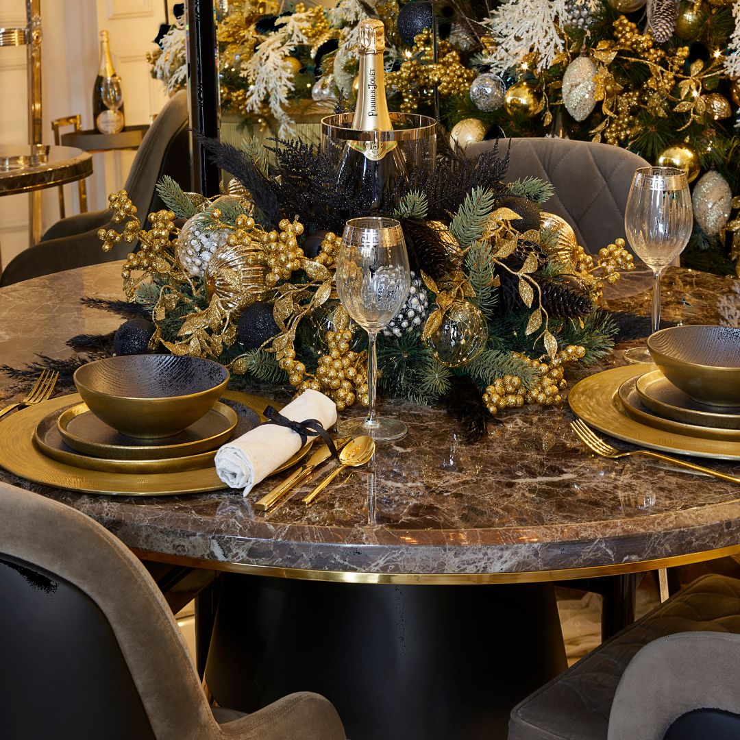 luxury dining table decorated with gold tableware and Christmas centrepiece