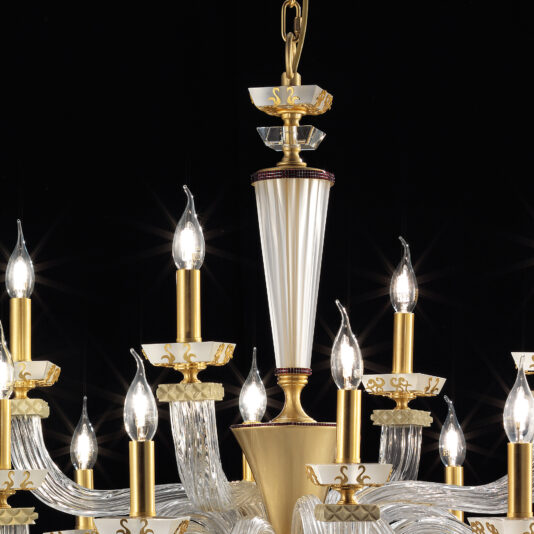 The Large Elegant Chandelier With Pendant Drops features gold accents, pendant drops, and multiple candle-shaped light bulbs. Its intricate designs and central white tapered section stand out against a black background, showcasing the chandelier's luxurious and ornate details.
