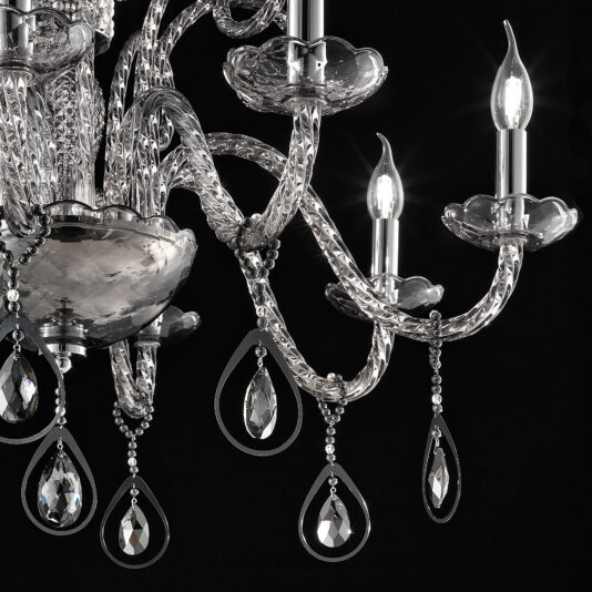 A close-up shot showcases the Smoked Glass Chandelier With Pendant Drops, highlighting its five candle-like lights. The chandelier boasts intricate glasswork and tear-shaped pendants, all gleaming brilliantly against a black background.