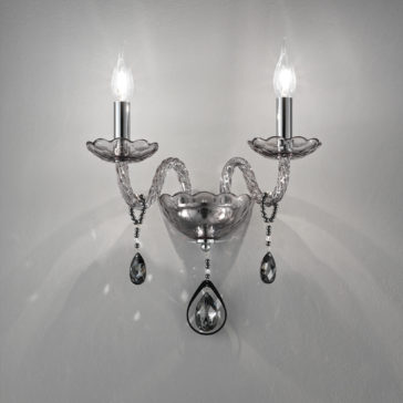 Smoked Glass Double Wall Light The Smoked Glass Double Wall Light is a stylish fixture with two illuminated bulbs, showcasing a sleek silver design. It features intricately curved arms, clear decorative elements, and dangling teardrop-shaped crystals, all set against a plain gray background.