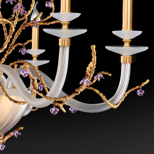 A close-up view of the Candle Style Chandelier With Swarovski Crystal Flowers showcases its elegant design, featuring gold branches adorned with purple Swarovski crystal flowers. The chandelier's white, curved glass arms and gold candle-like light holders stand out beautifully against a black background.