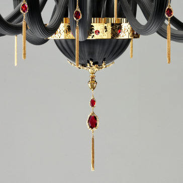 Classic Black Chandelier With Swarovski® Crystals The Classic Black Chandelier With Swarovski® Crystals boasts sophisticated, curved black arms and luxurious gold accents adorned with red gemstones. Thin gold pendant details hang from various points, adding an extra touch of opulence. Set against a plain and neutral background, this chandelier is truly a timeless masterpiece.