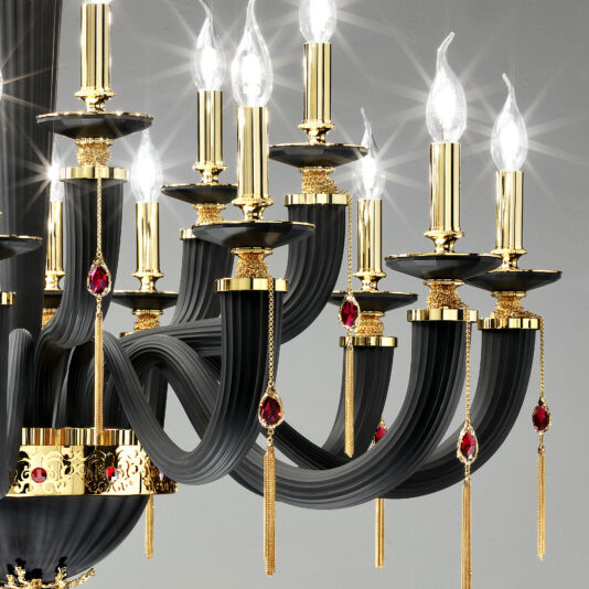 A close-up image of the Classic Black Chandelier With Swarovski® Crystals showcases its black curved arms adorned with golden accents and red gemstone details. Each arm supports a candle-like light bulb that emits a bright glow, exuding an air of luxury and opulence through its sophisticated design.